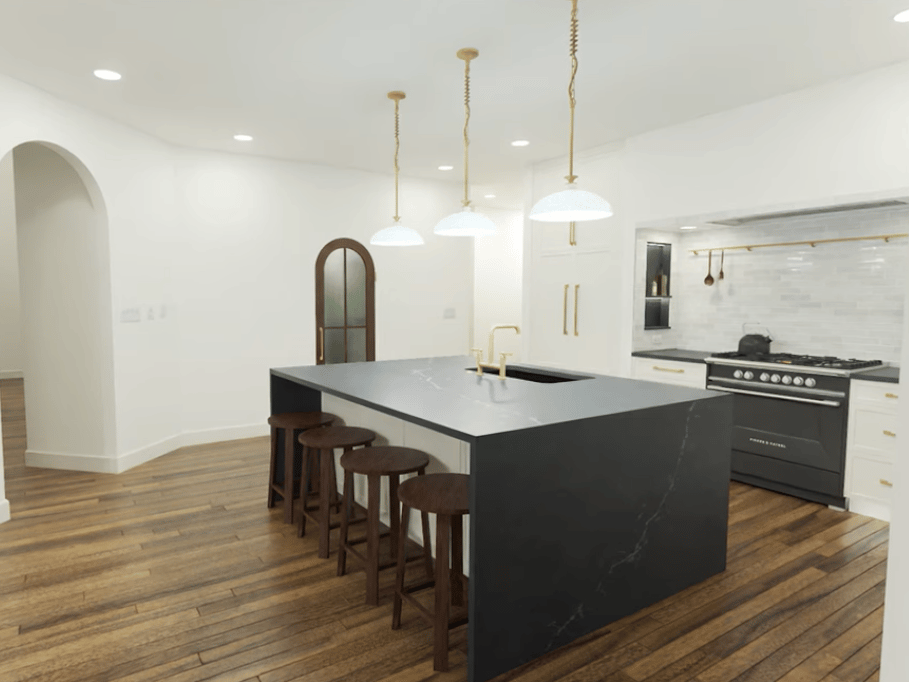 Waterfall island in a white kitchen with gold fixtures