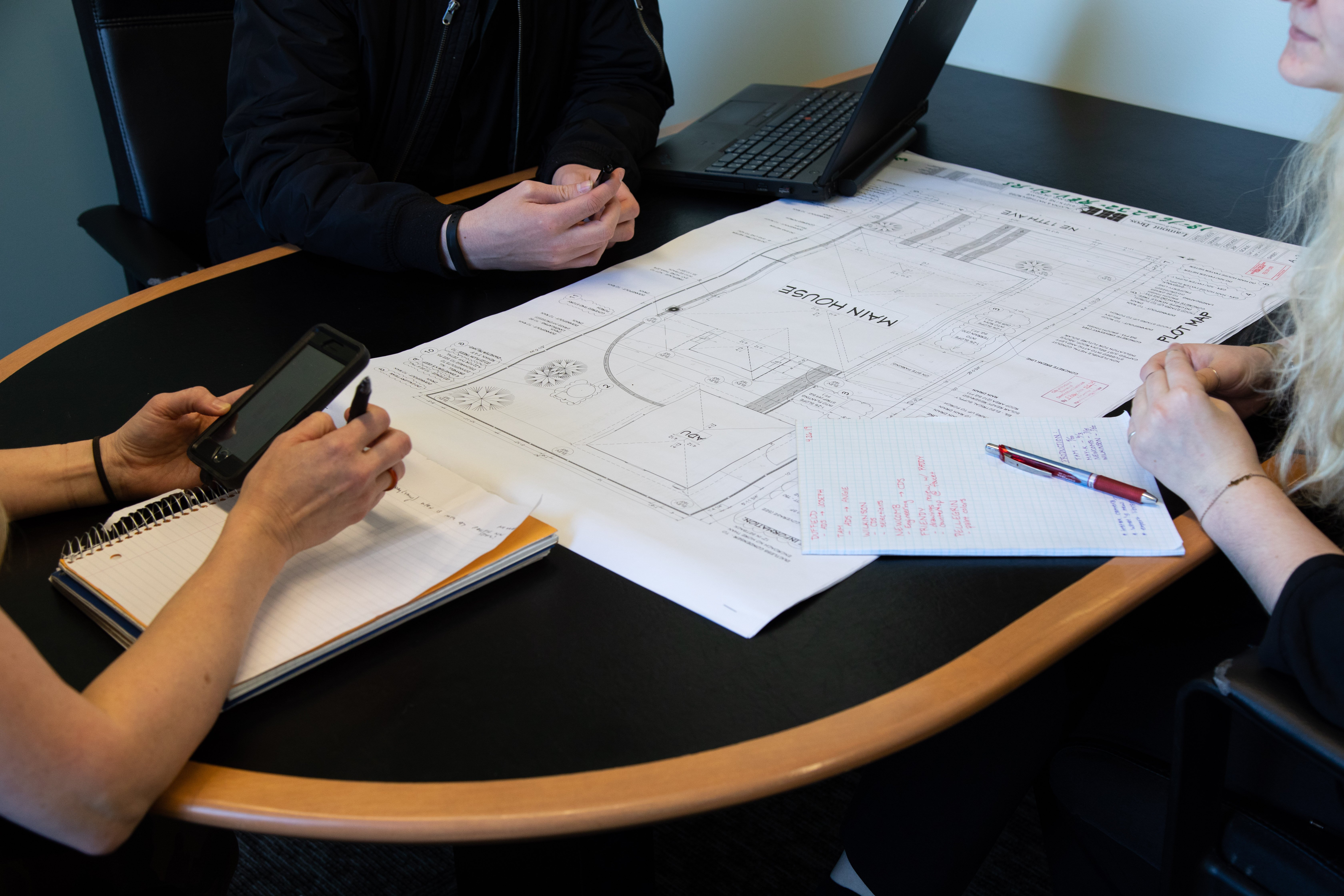 home renovation timeline: people working around table with remodel plans