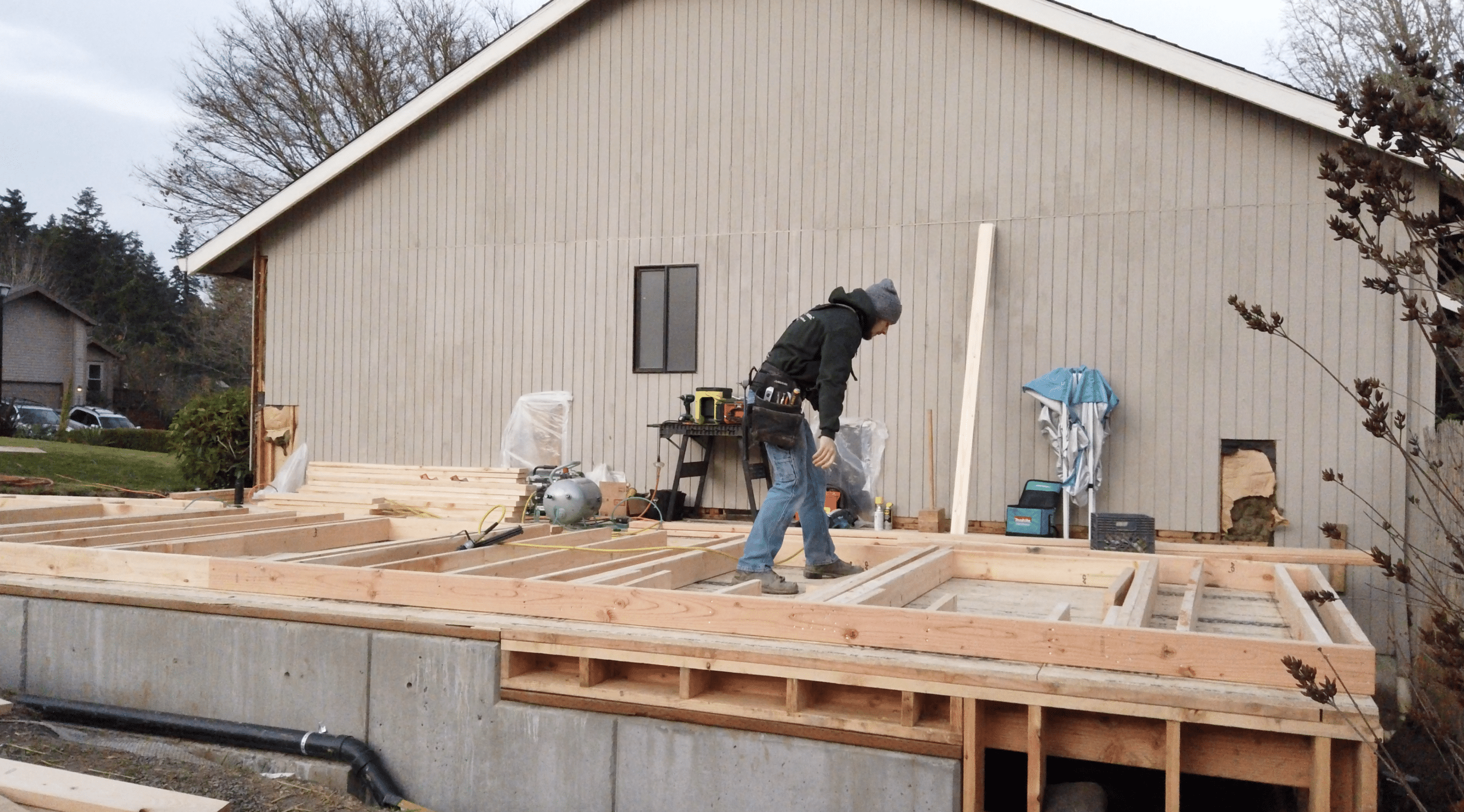 home renovation timelime: product delays. Worker installing wood framing on new addition
